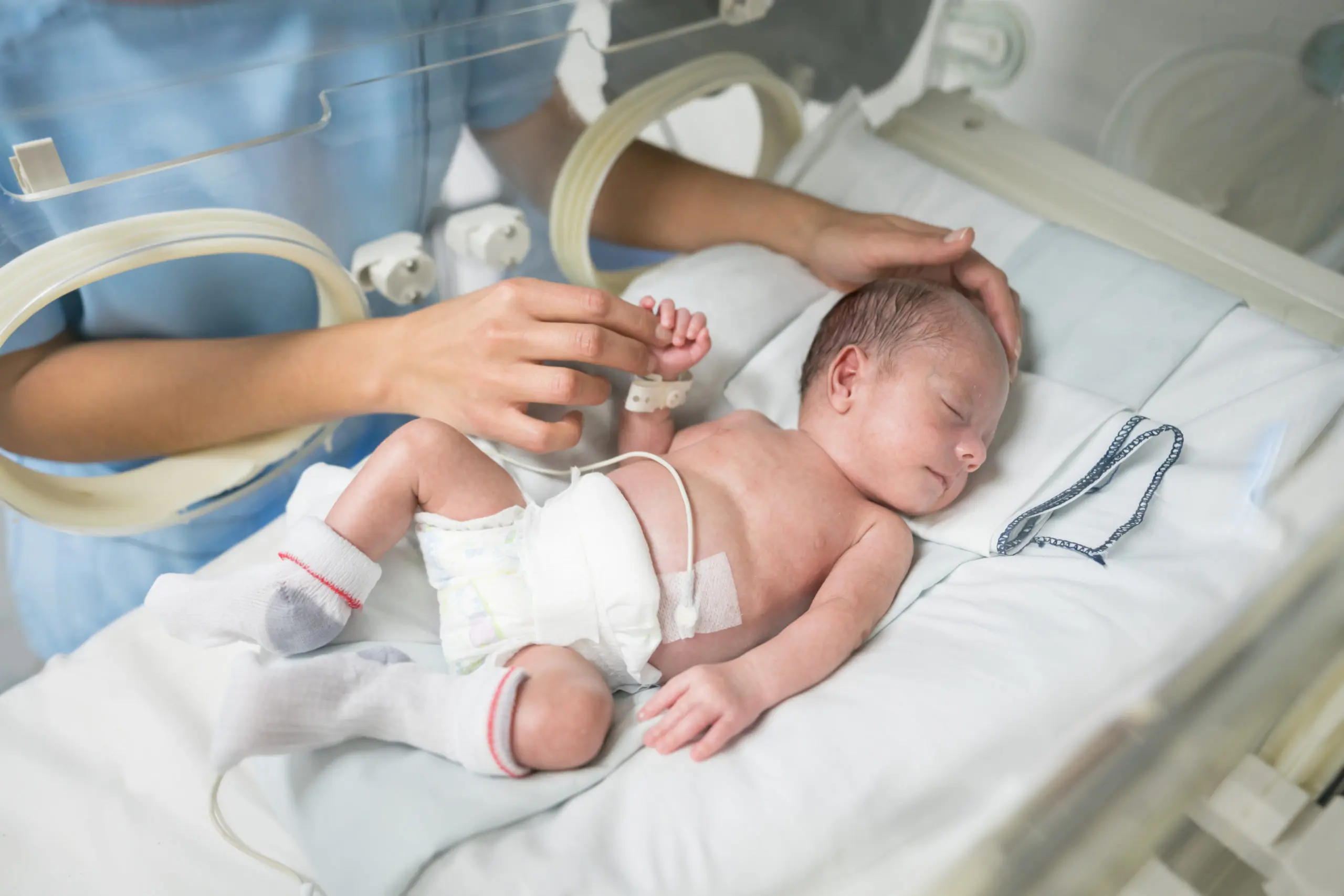 Unrecognizable nurse caressing a newborn baby in an incubator while he sleeps very peacefully