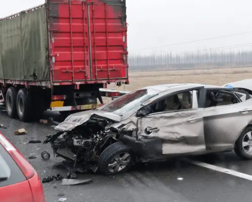Severe collision between a car and a large truck on a highway