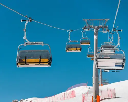 Empty ski lift chairs over snowy slope under clear blue sky representing ski resort safety concerns