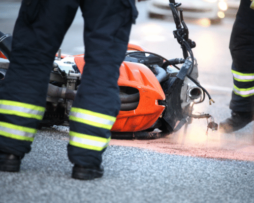 Emergency responders examine a crashed motorcycle on a roadway, representing internal injuries and trauma risks after Colorado motorcycle accidents.