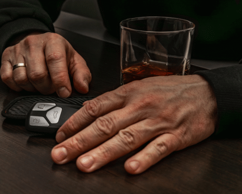 Driver’s hand resting near car keys beside a glass of alcohol, illustrating the dangers of impaired driving and the type of reckless behavior that can support punitive damages claims in Denver DUI accident cases.
