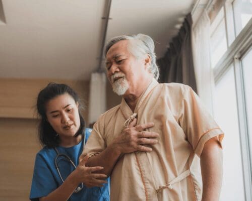 Healthcare worker assisting elderly man experiencing chest pain