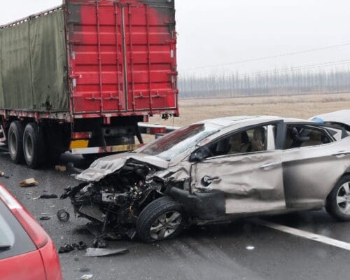 Severe collision between a car and a large truck on a highway