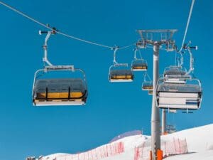 Empty ski lift chairs over snowy slope under clear blue sky representing ski resort safety concerns
