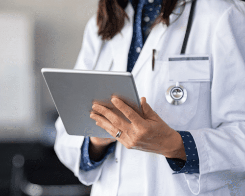 Female doctor in white coat reviewing patient information on a tablet, representing modern healthcare technology and potential delays in medical diagnosis