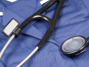 Close-up of a black stethoscope resting on blue medical scrubs with a blank name tag, symbolizing healthcare professionalism and patient care