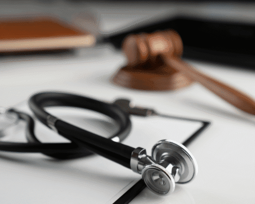Close-up of a stethoscope and judge’s gavel on a desk, representing legal action in medical malpractice cases