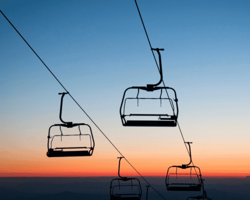Empty ski lift chairs silhouetted against a colorful Colorado sunset sky, representing the landmark Annie Miller ski lift accident case where a jury awarded $20 million in damages for negligence at Crested Butte ski resort.