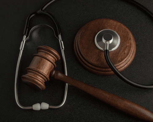 A wooden gavel rests beside a stethoscope on a dark surface, symbolizing the intersection of medicine and law. The image represents wrongful death claims arising from surgical errors in Denver, highlighting the legal pursuit of justice for medical negligence and loss.