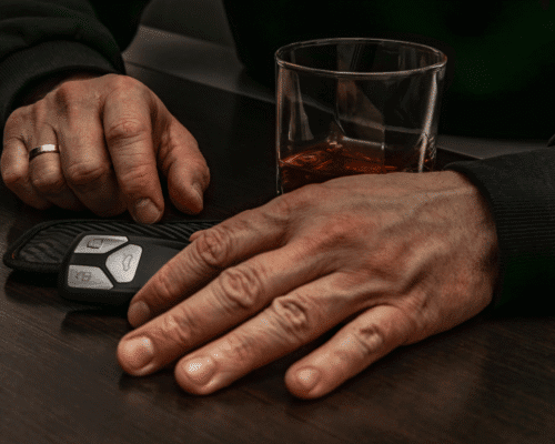 Driver’s hand resting near car keys beside a glass of alcohol, illustrating the dangers of impaired driving and the type of reckless behavior that can support punitive damages claims in Denver DUI accident cases.