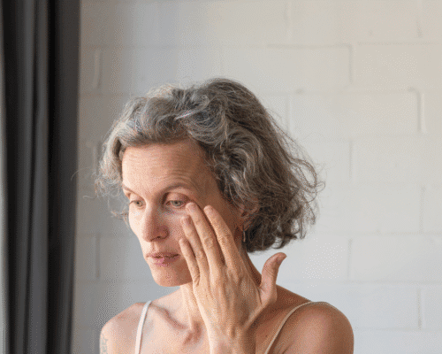 A concerned woman touching her eye, illustrating vision complications or discomfort following eye surgery and the potential impact of ophthalmological errors.