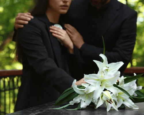 Family members mourning beside a casket with white lilies, representing grief and the potential for a wrongful death lawsuit following a kratom-related death.